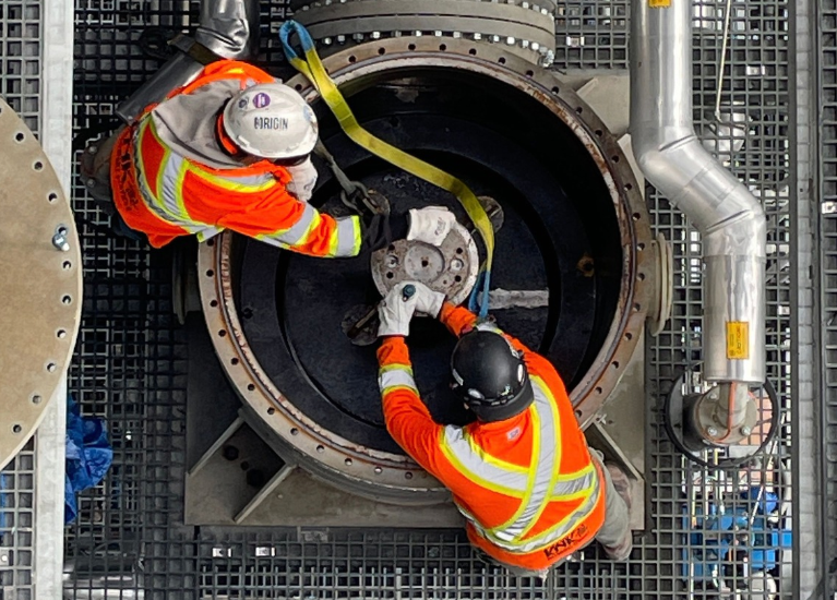 Two Millwrights in high-visibility workwear working on industrial machinery.