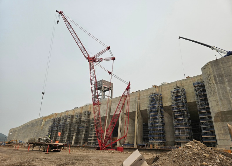 Cranes beside a large concrete structure under construction.
